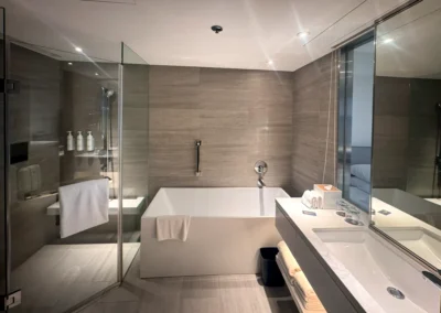 Modern bathroom at Courtyard Taipei Downtown featuring a soaking tub, glass-enclosed shower, and large vanity.