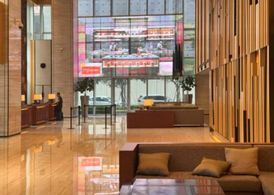 Courtyard Taipei Downtown modern hotel lobby with MJ Kitchen ad on screen and front desk area.