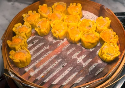 Steamed pork siu mai dumplings in a bamboo steamer.