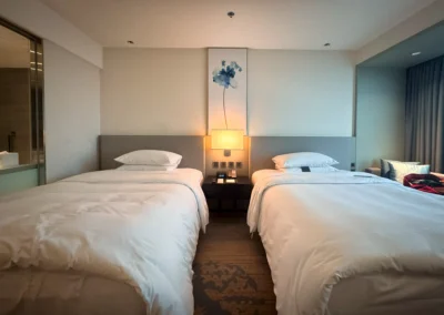 Twin bed room at Courtyard Taipei Downtown featuring minimalist decor, soft lighting, and a large floral painting above the nightstand.