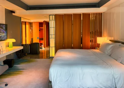 Bedroom area of the Fabulous Room, Corner Unit at W Taipei, showcasing a plush king bed, warm lighting, and contemporary wood paneling.