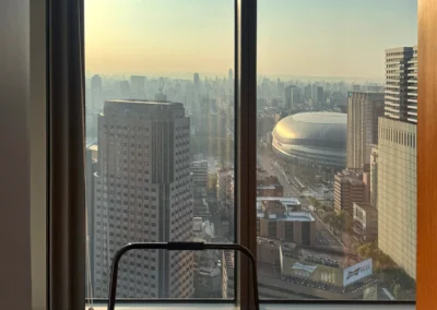 Window view from the W Taipei Fabulous Room corner unit, overlooking Taipei Dome and the city skyline at sunset.