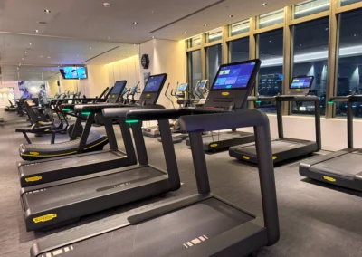 Row of high-end treadmills in the FIT gym at W Taipei, equipped with touchscreen displays and a city view.