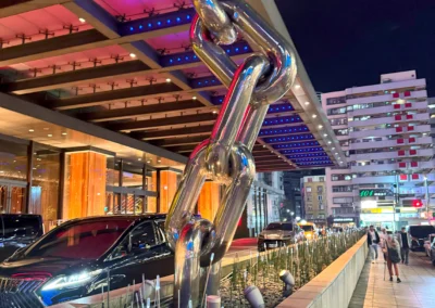 W Taipei hotel entrance at night, featuring the iconic oversized chrome chain sculpture and illuminated canopy.