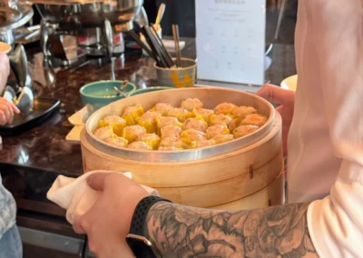 Freshly steamed siu mai dim sum served at YEN restaurant in W Taipei's breakfast buffet, delivered in a traditional bamboo steamer by a staff member.